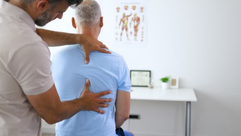 Doctor physiotherapist doing healing treatment on man's back.Back pain patient, treatment, medical doctor, massage therapist.